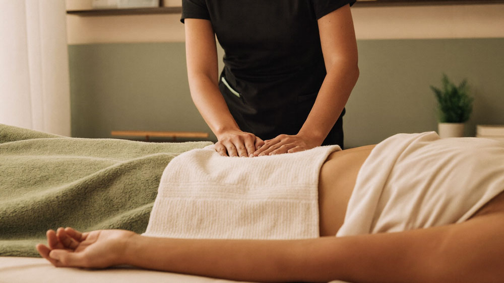 Massage therapist working gently over a patient's abdomen during scar tissue treatment